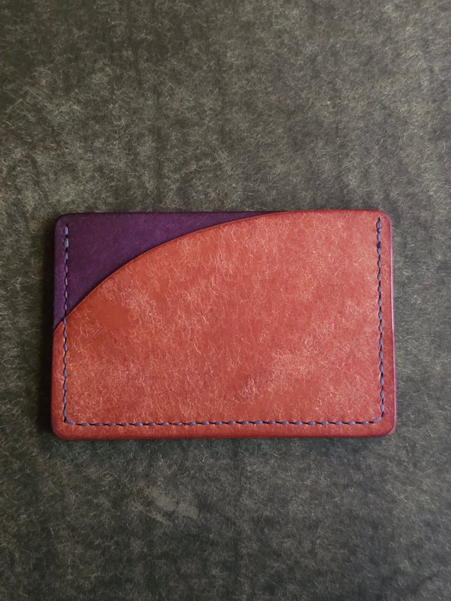 Back of leather card holder with pocket shaped like a sunset.