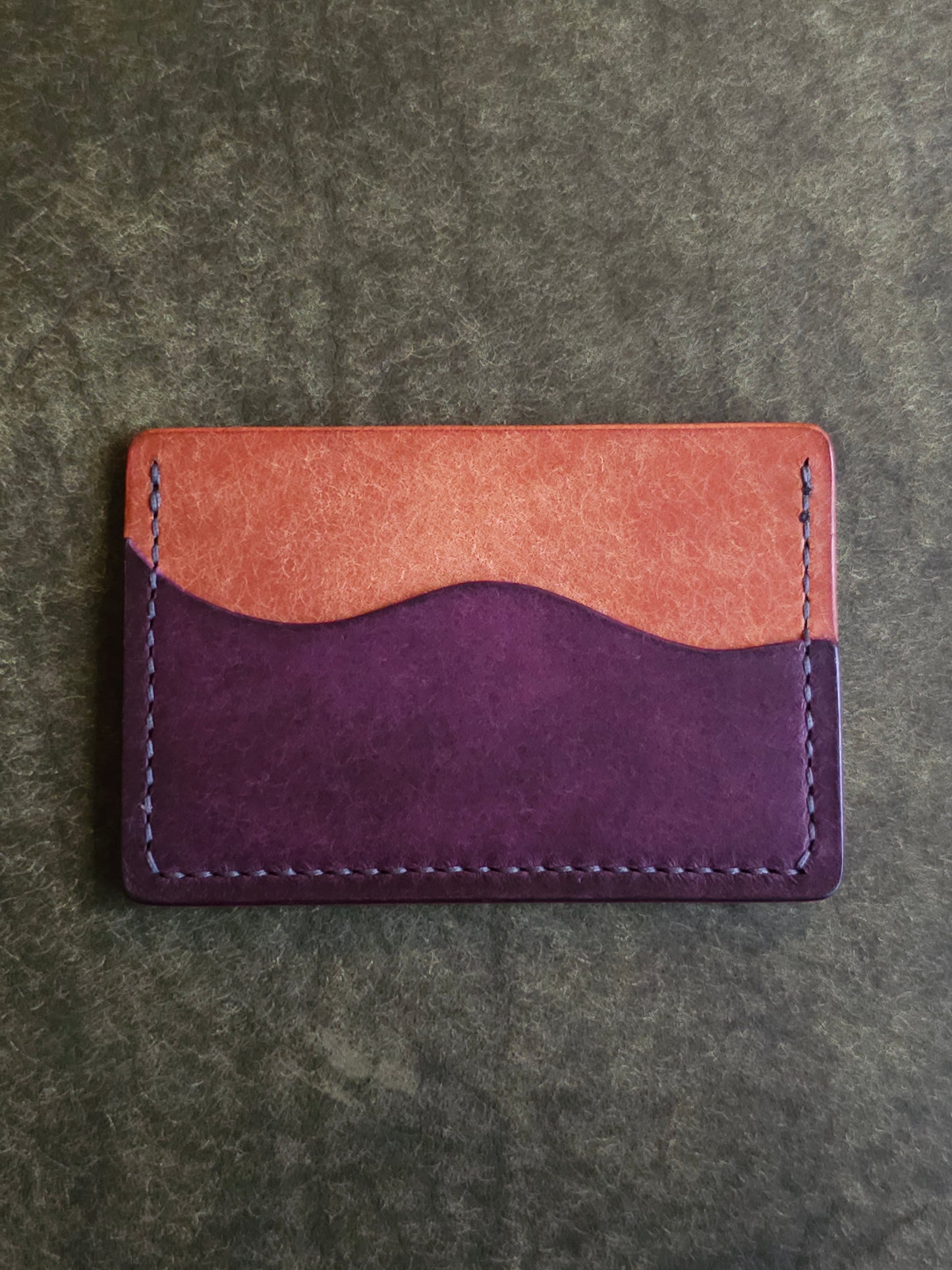 Back of leather card holder with pocket shaped like a wave.