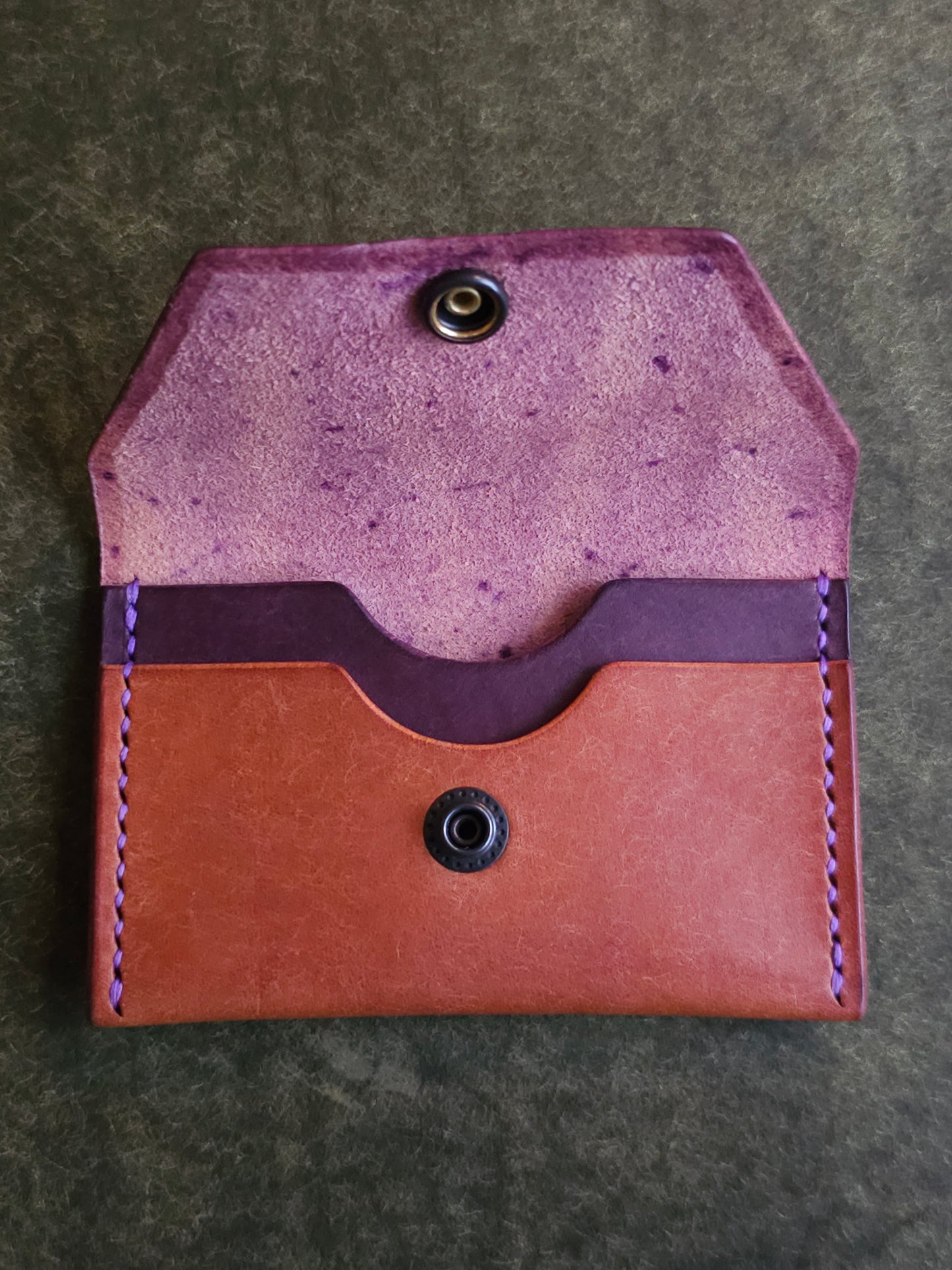 Inside of leather card holder with the snap is unbuttoned. There are two interior pockets showing.