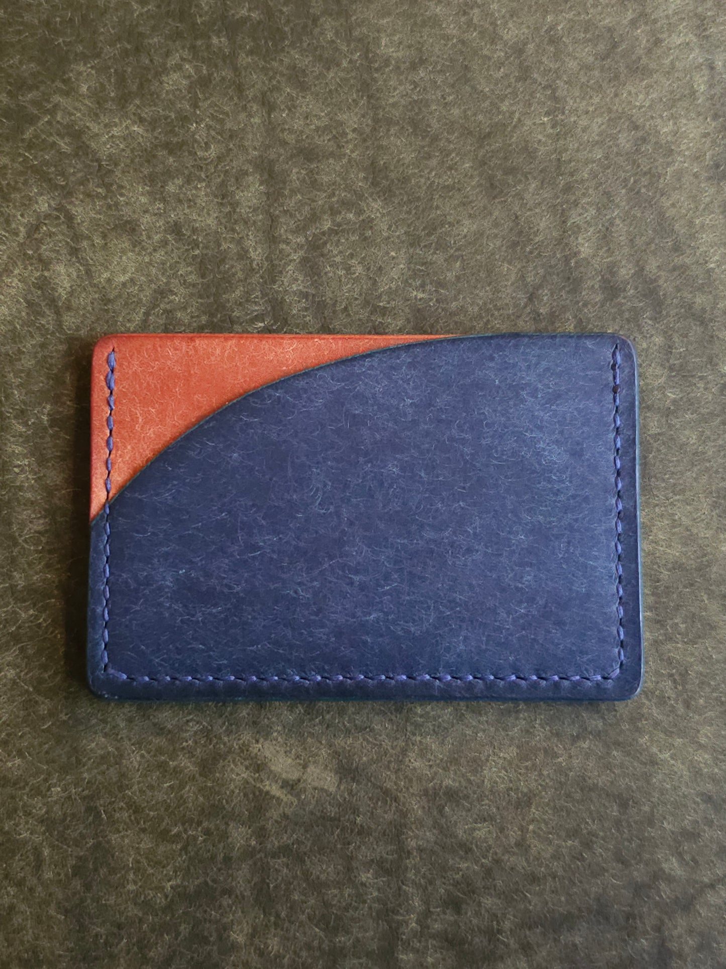 Back of leather card holder with pocket shaped like a sunset.