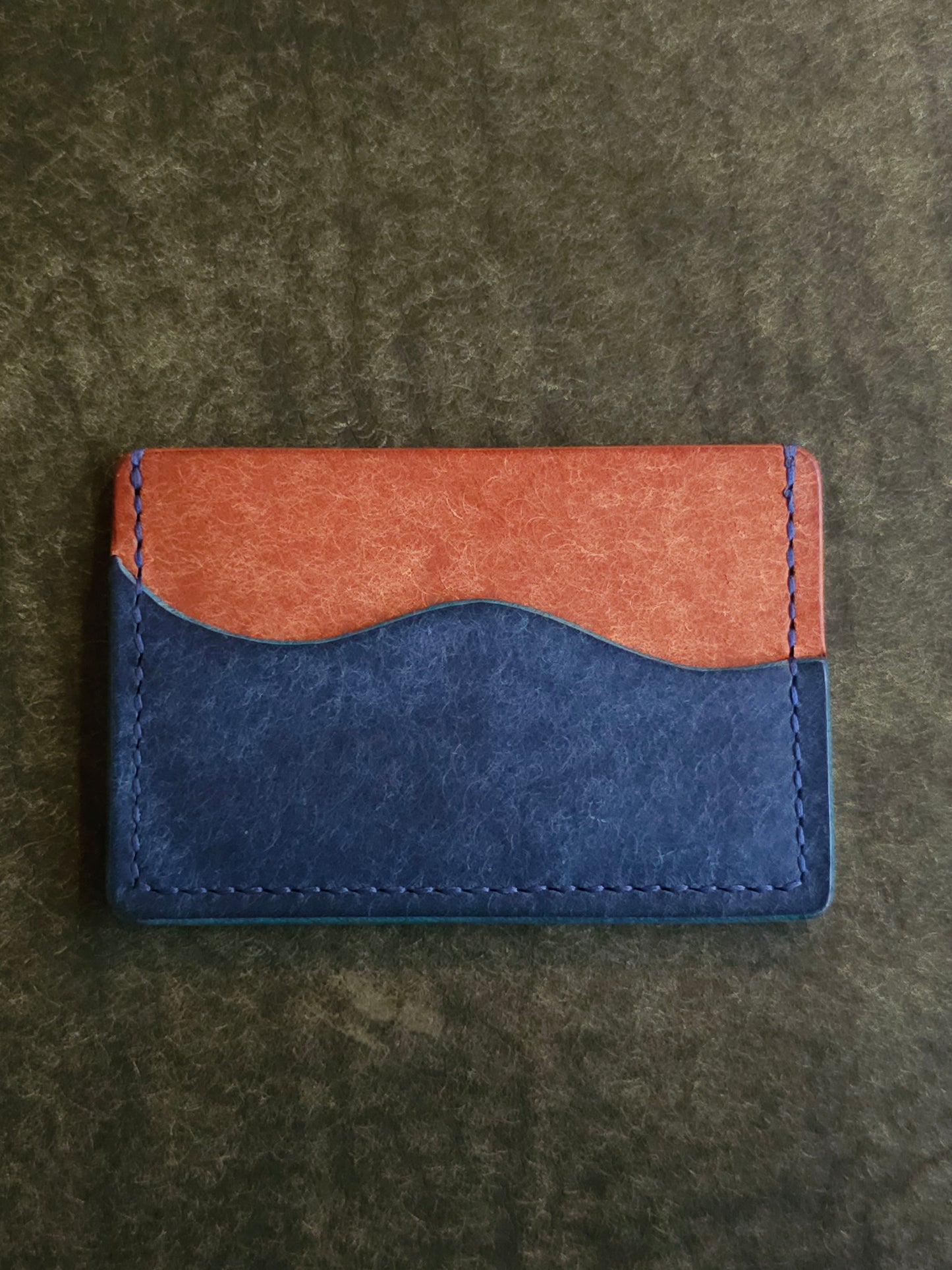 Leather card holder with pocket shaped like a wave. Wayward Souls logo is stamped in the bottom right corner of the wallet.