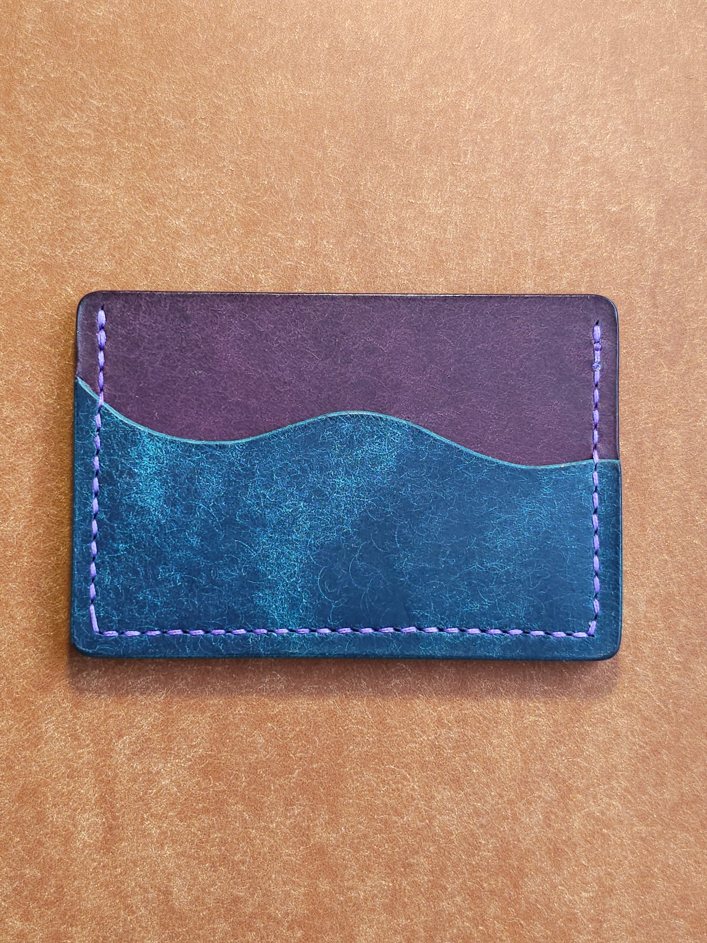 Back of leather card holder with pocket shaped like a wave.