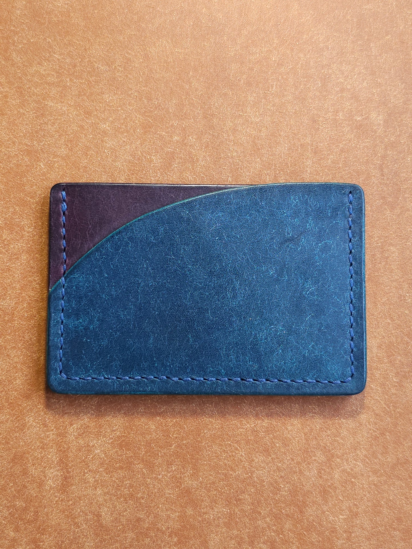 Back of leather card holder with pocket shaped like a sunset.