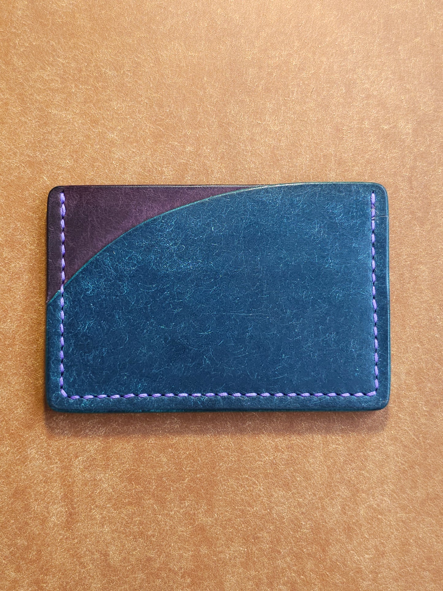 Back of leather card holder with pocket shaped like a sunset.