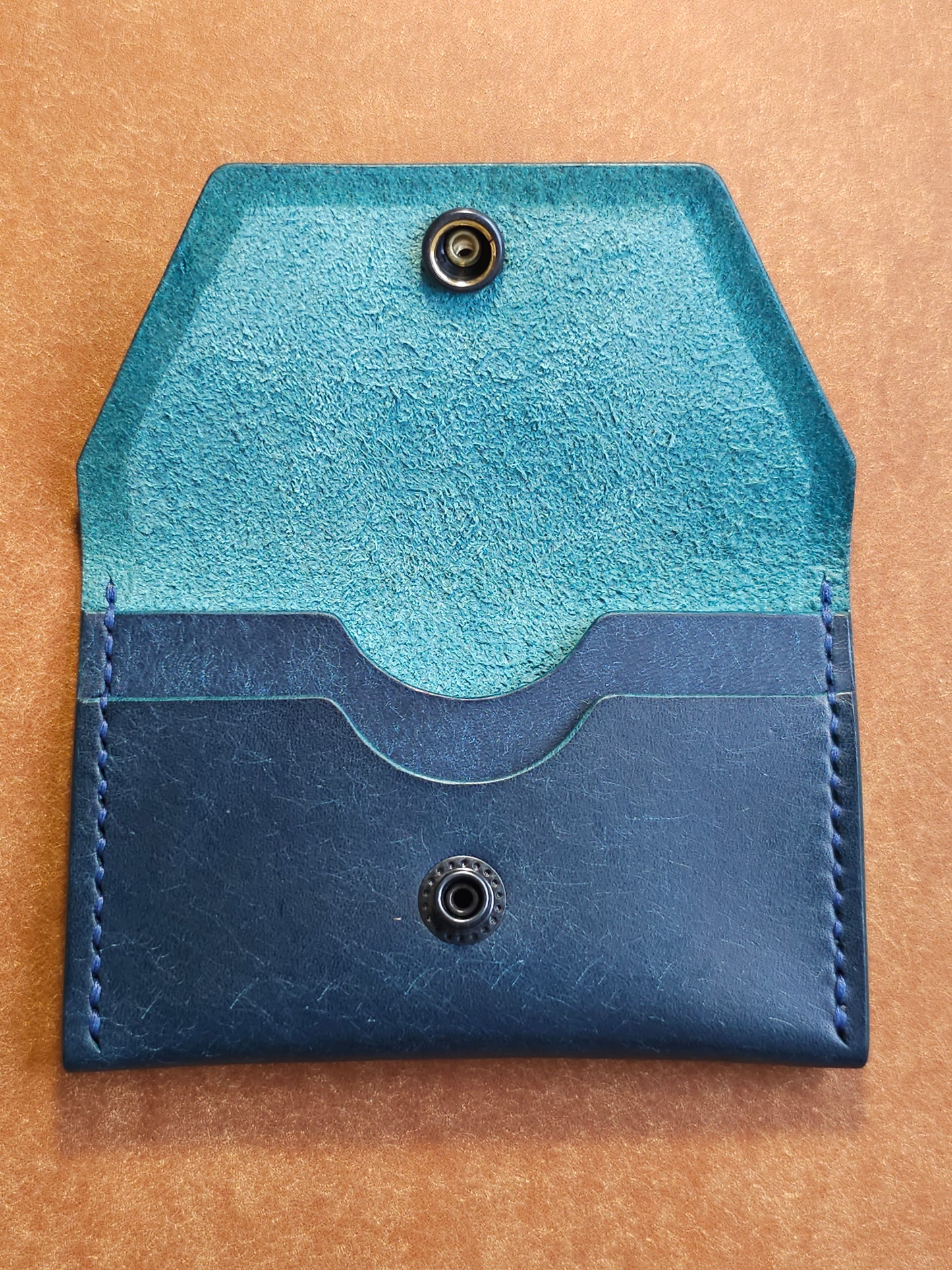 Inside of leather card holder with the snap unbuttoned. There are two interior pockets showing.