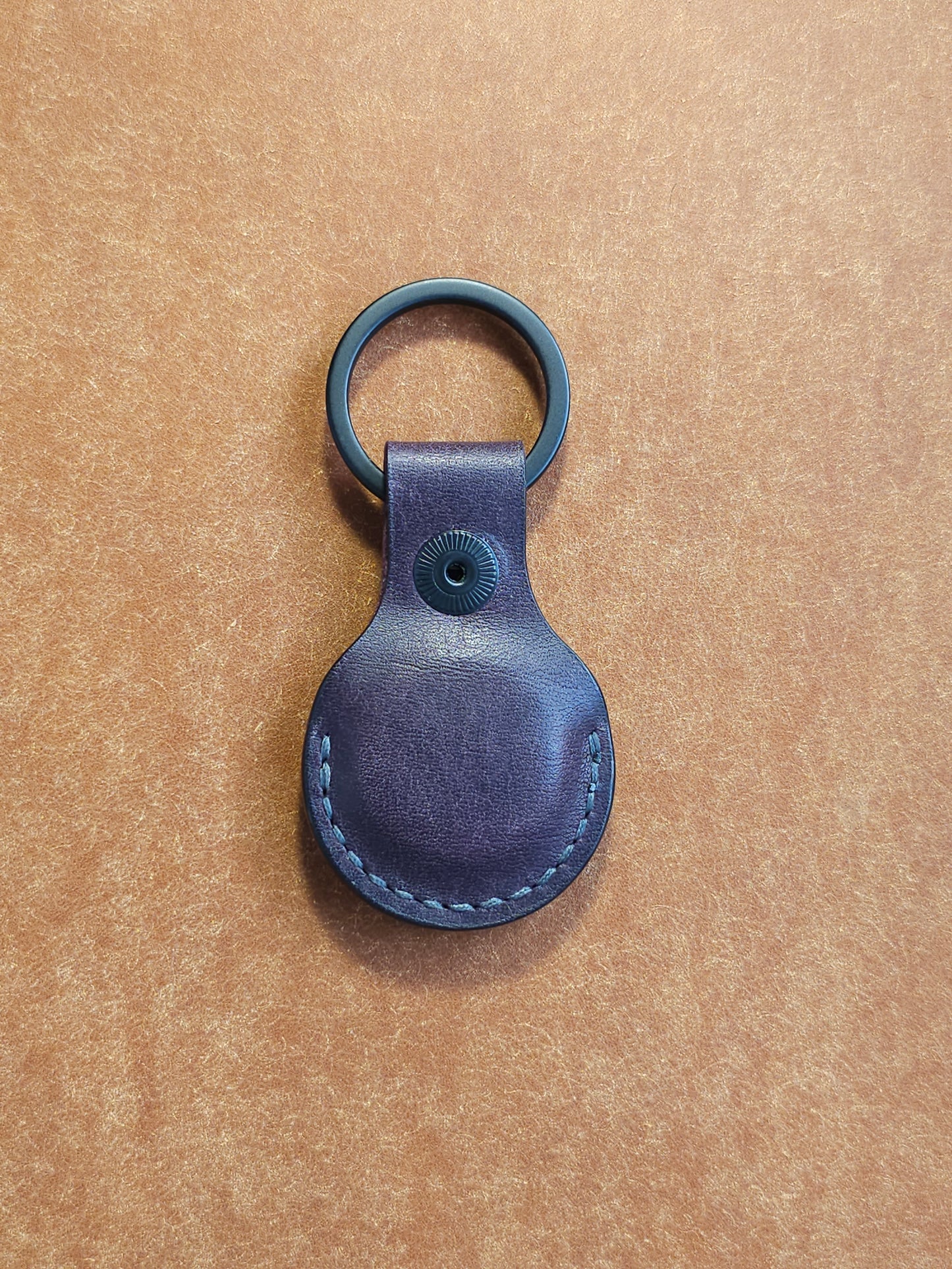 Back of circular leather air tag holder attached to black key ring.
