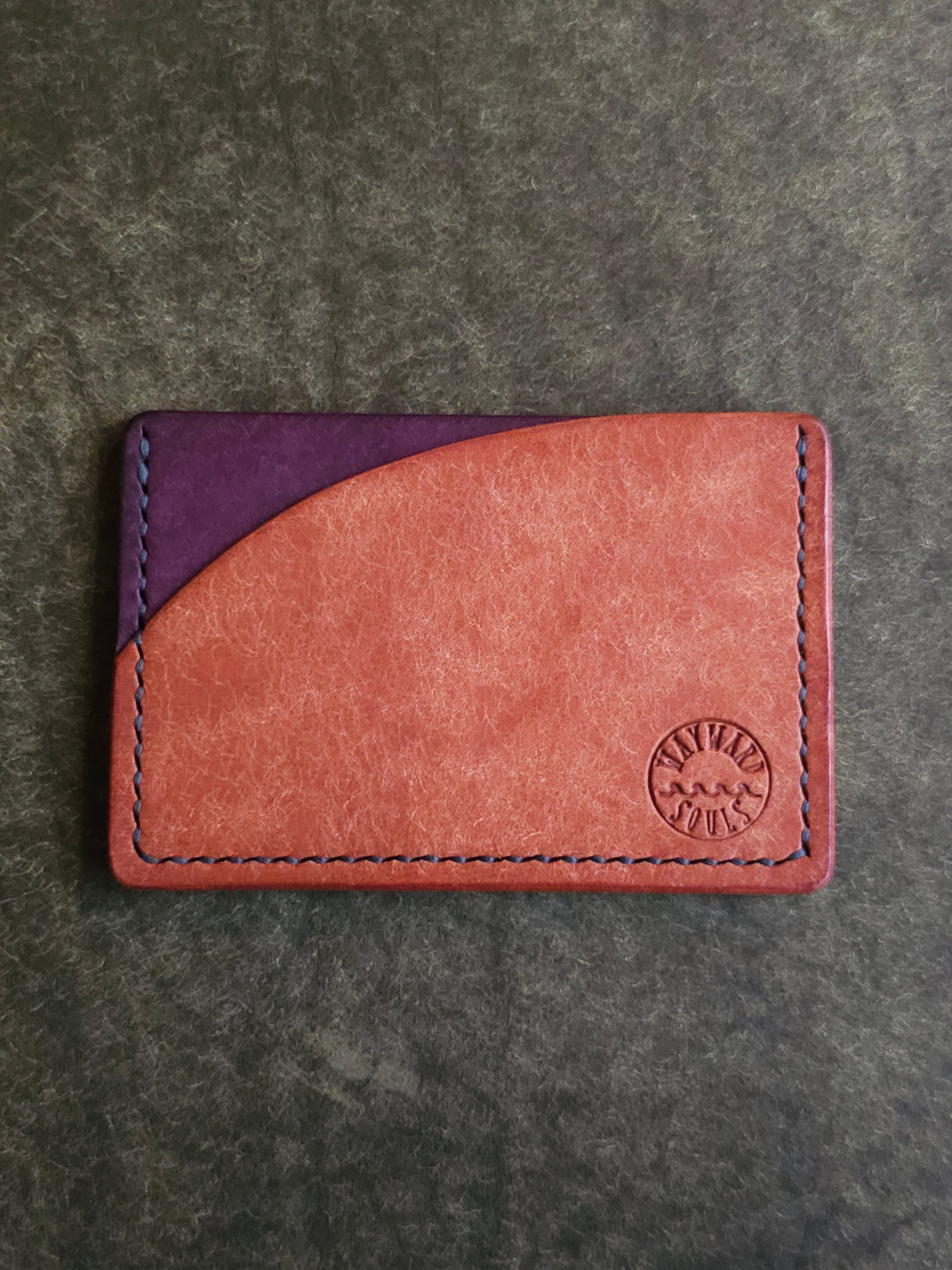 Leather card holder with pocket shaped like a sunset. Wayward Souls logo is stamped in the bottom right corner of the wallet.