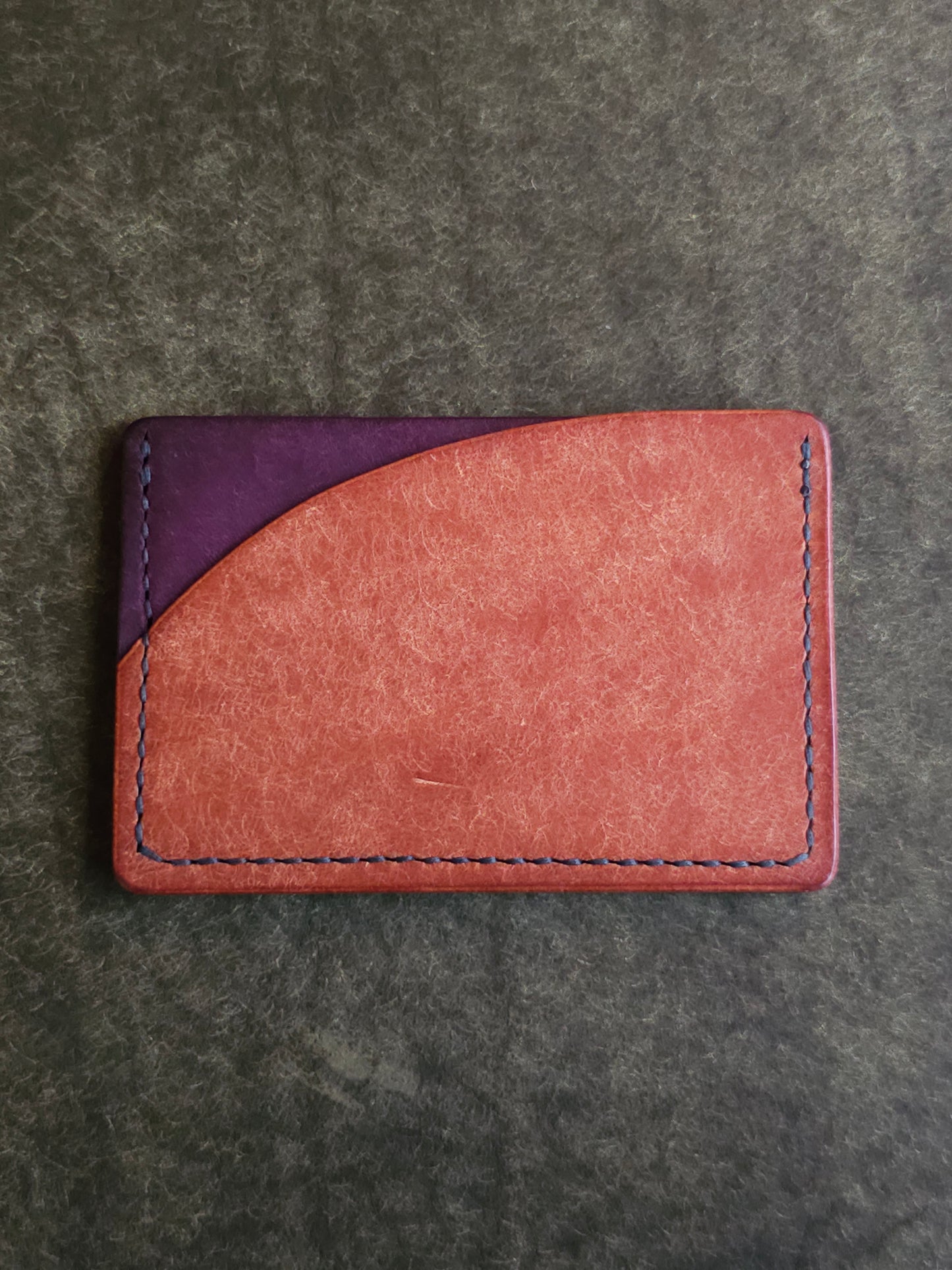 Back of leather card holder with pocket shaped like a sunset.