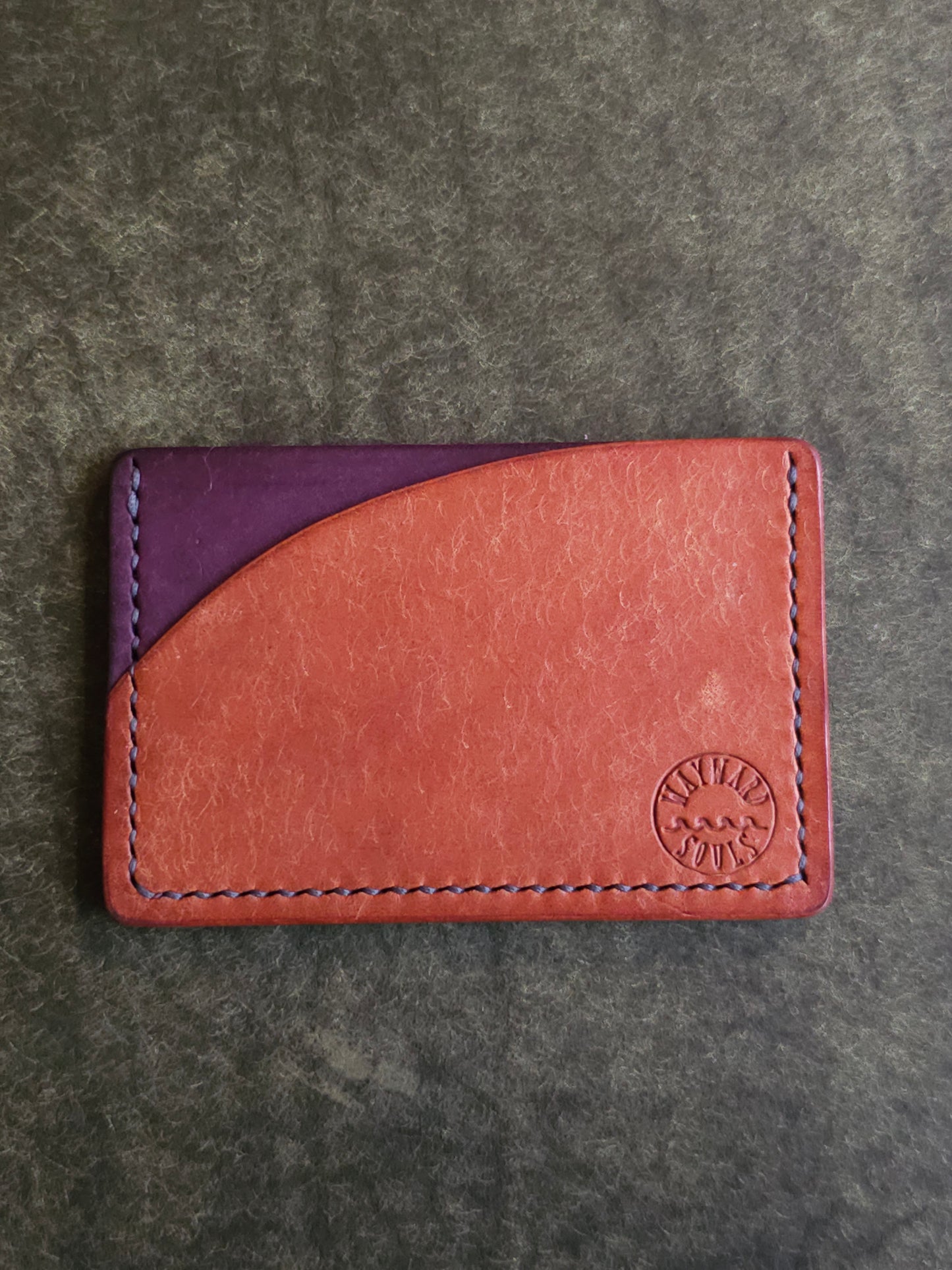 Leather card holder with pocket shaped like a sunset. Wayward Souls logo is stamped in the bottom right corner of the wallet.