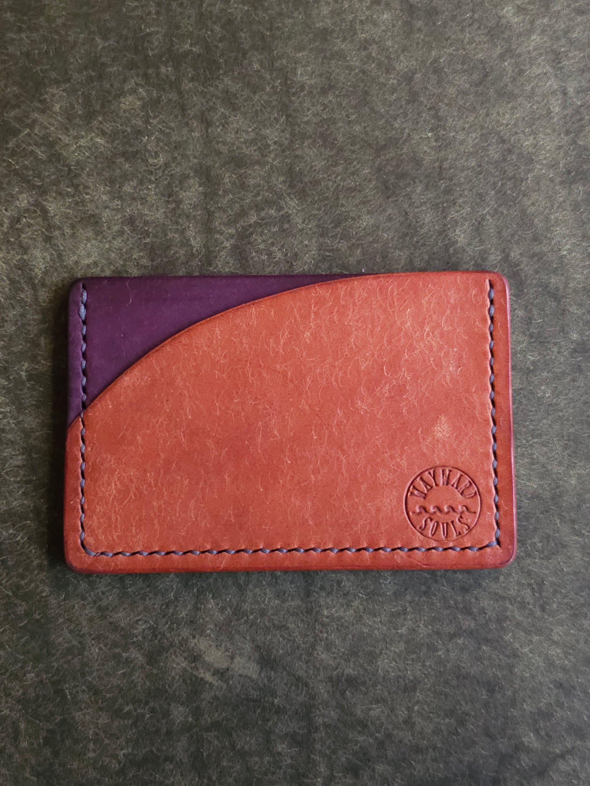 Leather card holder with pocket shaped like a sunset. Wayward Souls logo is stamped in the bottom right corner of the wallet.
