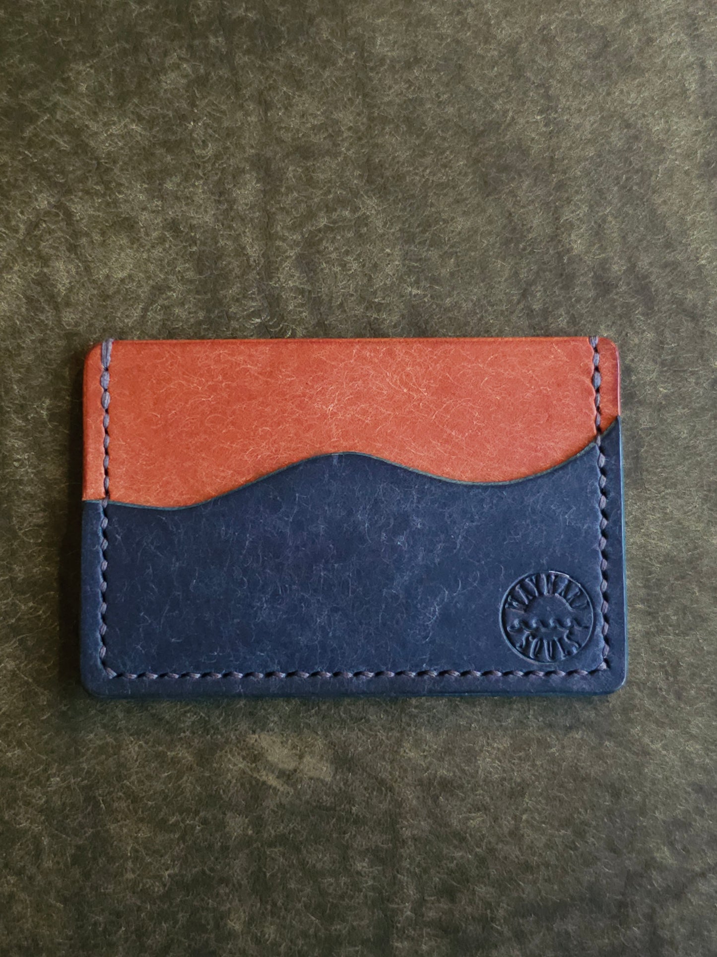 Leather card holder with pocket shaped like a wave. Wayward Souls logo is stamped in the bottom right corner of the wallet.