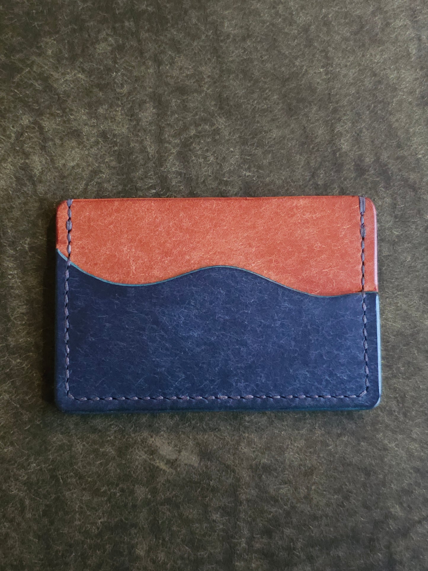 Back of leather card holder with pocket shaped like a wave.