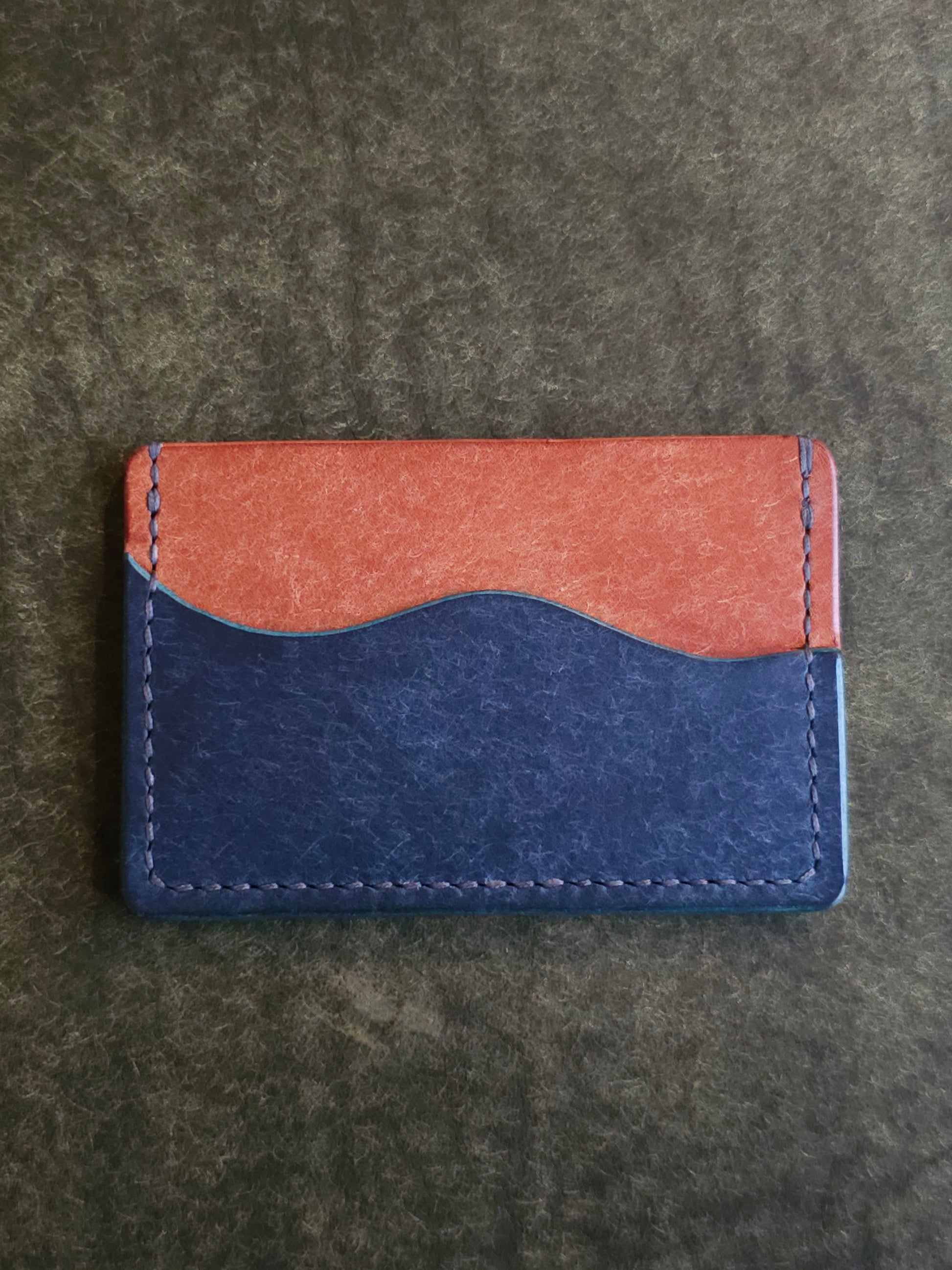 Back of leather card holder with pocket shaped like a wave.