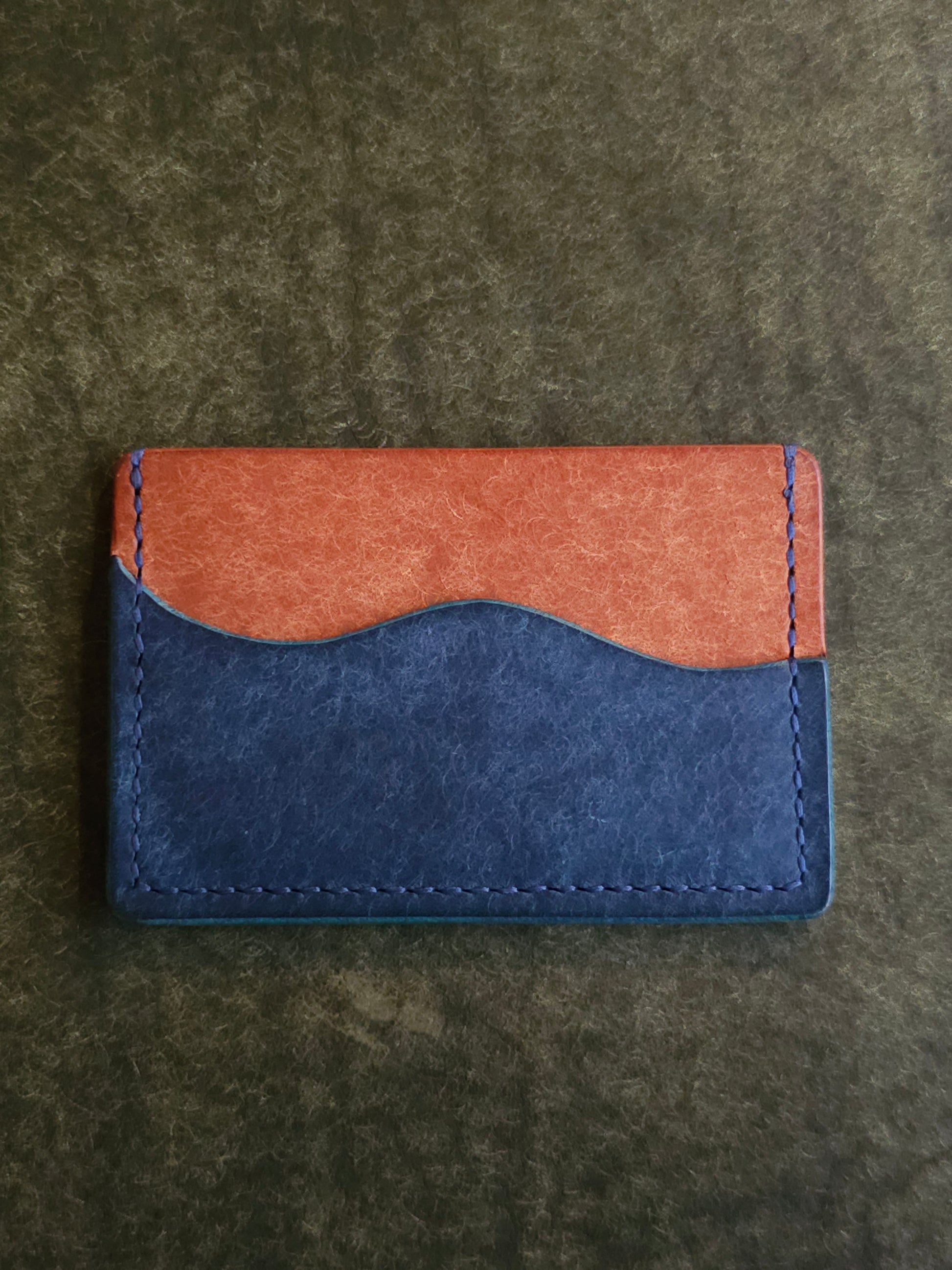Leather card holder with pocket shaped like a wave. Wayward Souls logo is stamped in the bottom right corner of the wallet.