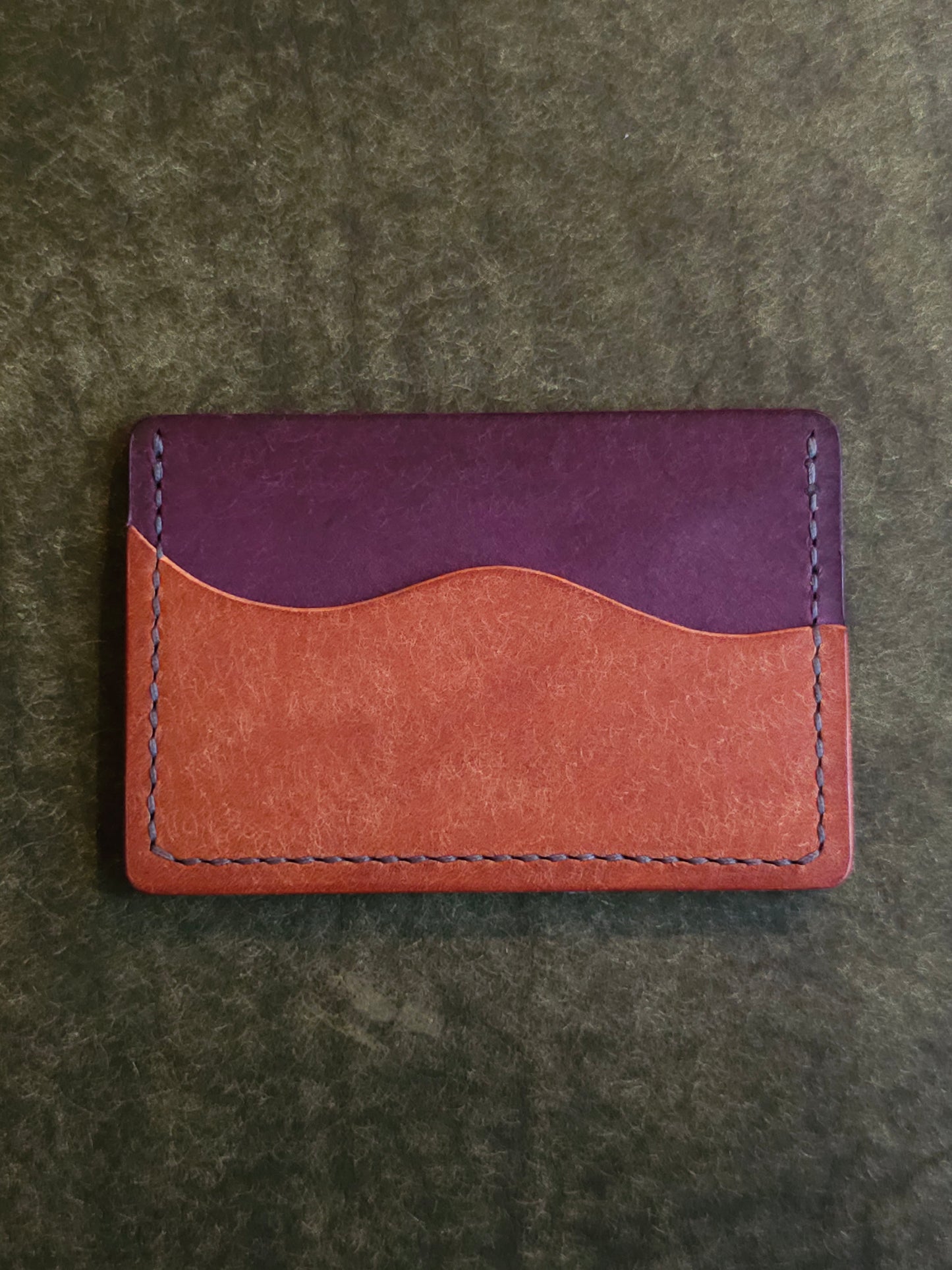 Back of leather card holder with pocket shaped like a wave.