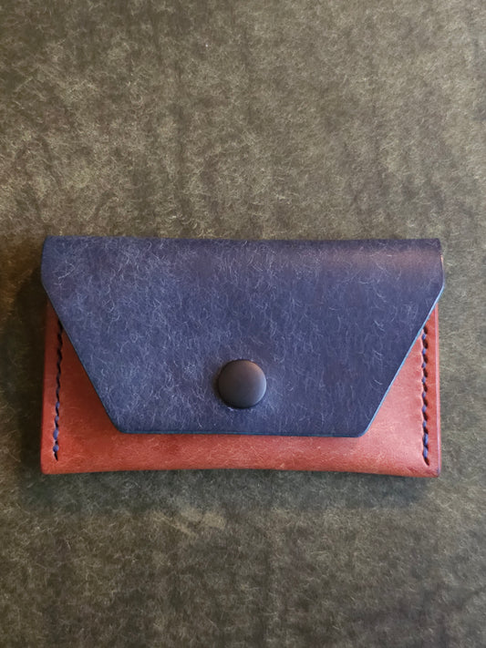 Front of leather card holder with angled pocket fastened with a snap.