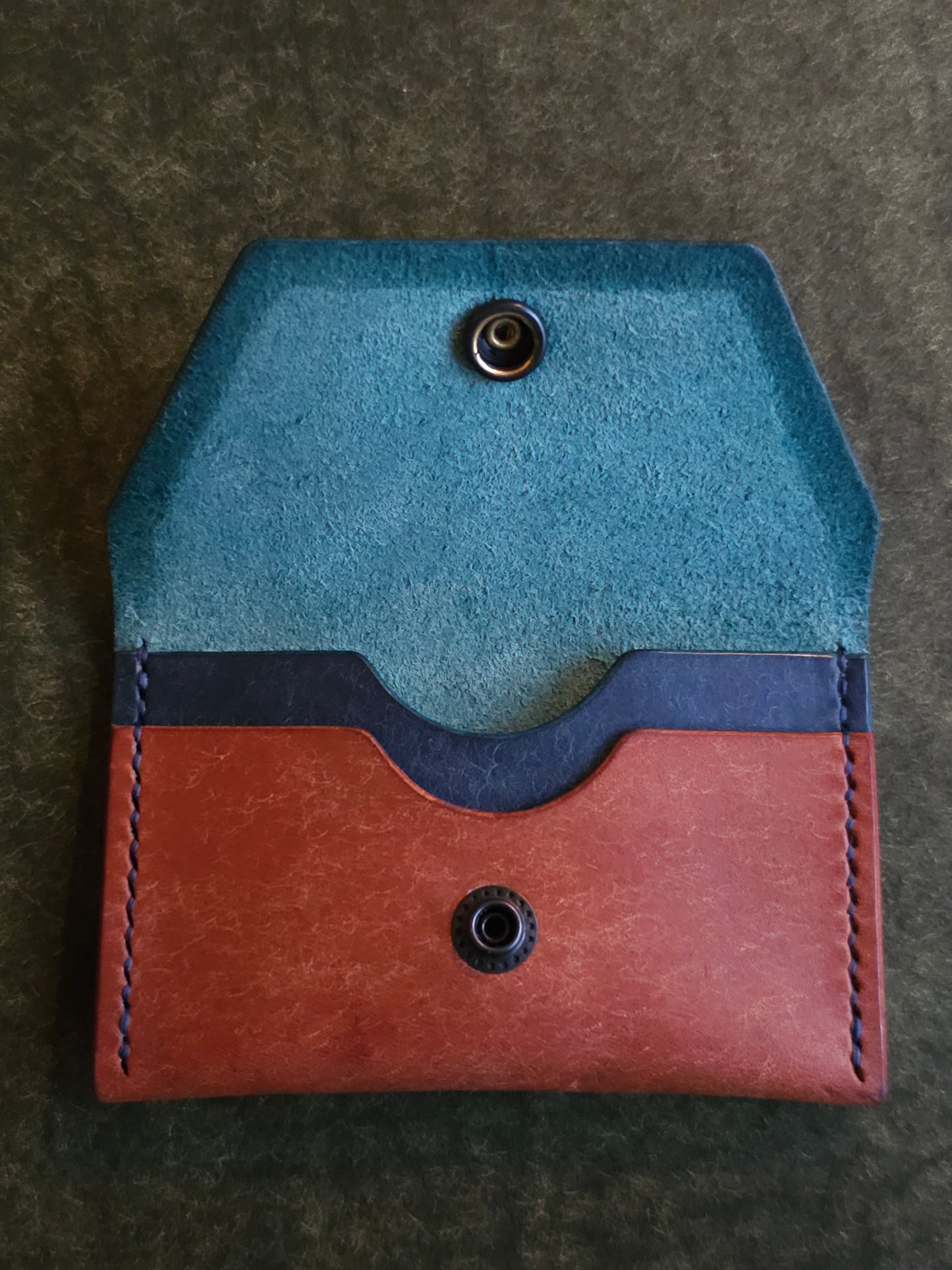 Inside of leather card holder with the snap is unbuttoned. There are two interior pockets showing.