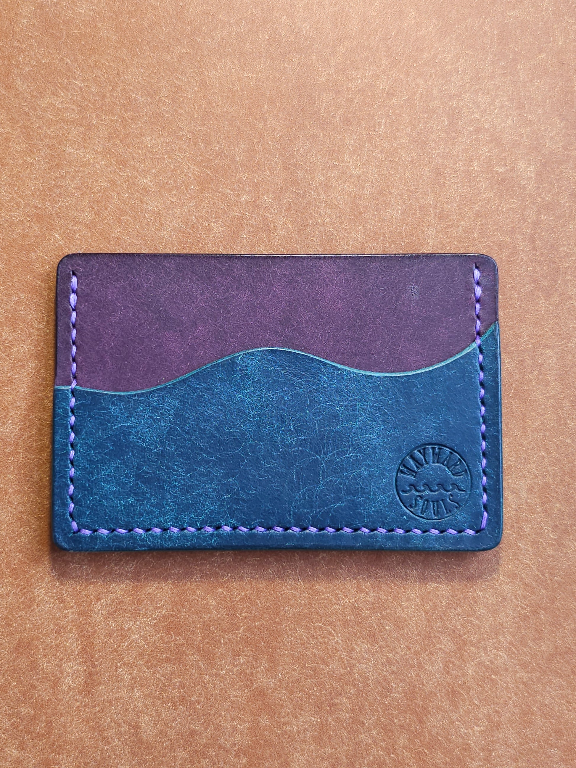 Leather card holder with pocket shaped like a wave. Wayward Souls logo is stamped in the bottom right corner of the wallet.