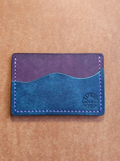 Leather card holder with pocket shaped like a wave. Wayward Souls logo is stamped in the bottom right corner of the wallet.