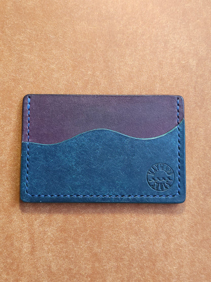 Leather card holder with pocket shaped like a wave. Wayward Souls logo is stamped in the bottom right corner of the wallet.