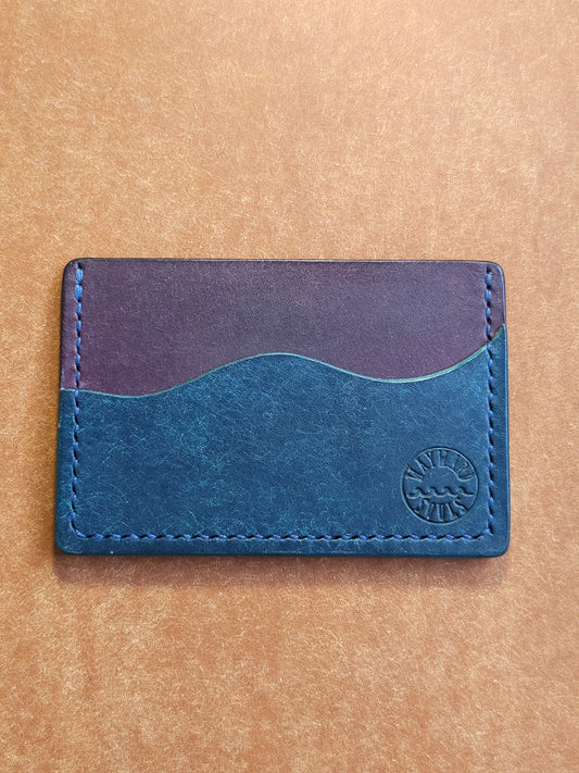 Leather card holder with pocket shaped like a wave. Wayward Souls logo is stamped in the bottom right corner of the wallet.