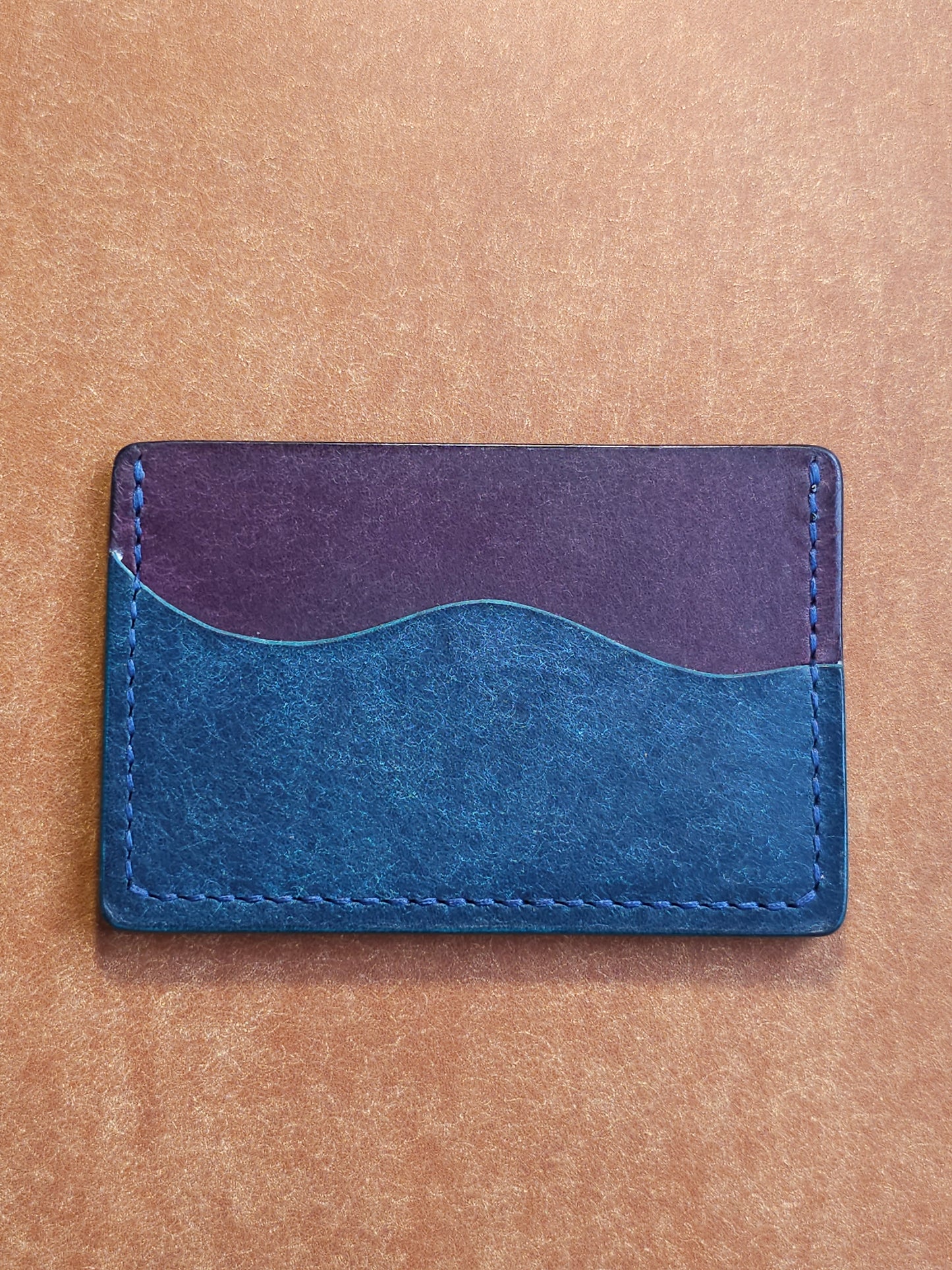 Back of leather card holder with pocket shaped like a wave.