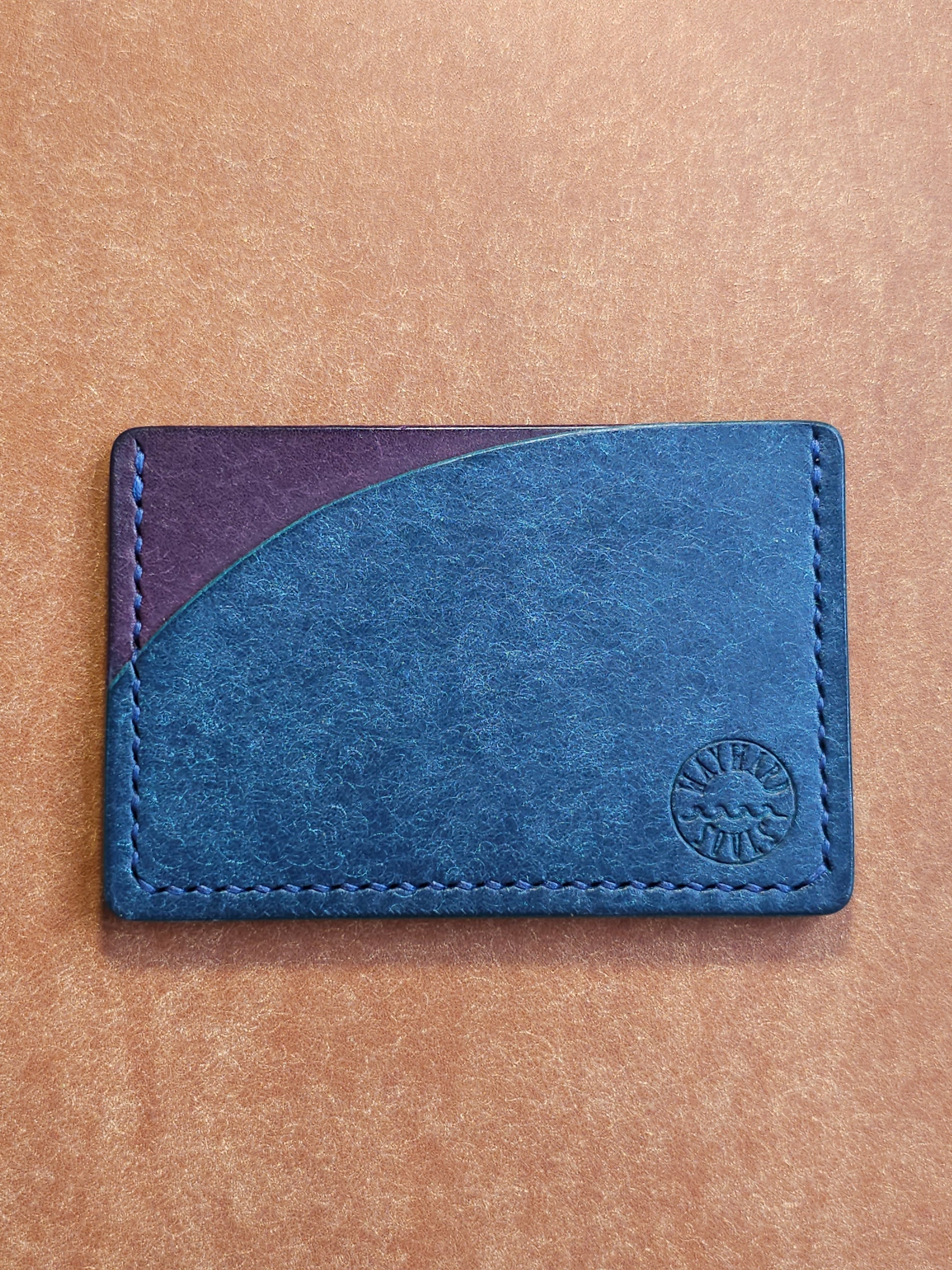Leather card holder with pocket shaped like a sunset. Wayward Souls logo is stamped in the bottom right corner of the wallet.