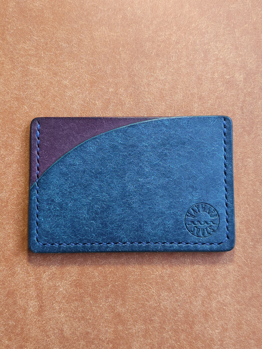 Leather card holder with pocket shaped like a sunset. Wayward Souls logo is stamped in the bottom right corner of the wallet.