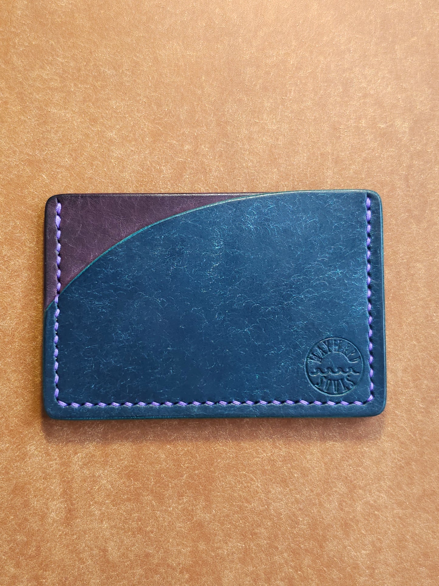 Leather card holder with pocket shaped like a sunset. Wayward Souls logo is stamped in the bottom right corner of the wallet.
