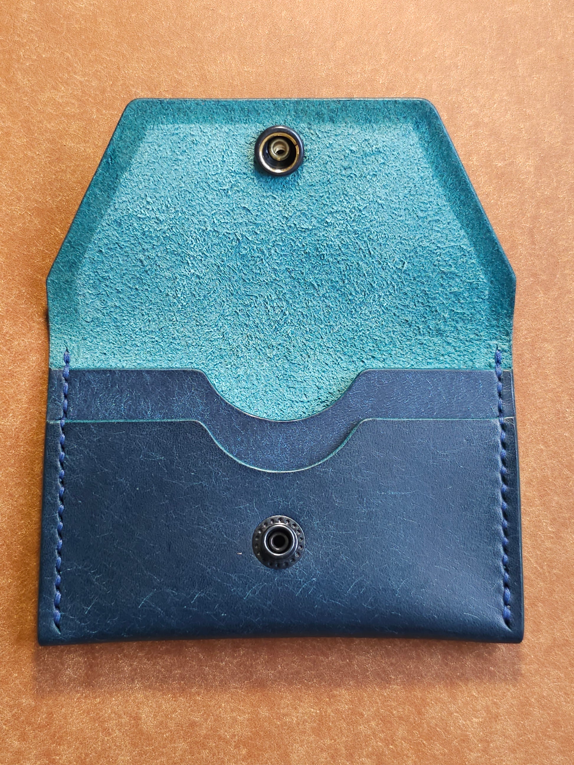 Inside of leather card holder with the snap unbuttoned. There are two interior pockets showing.