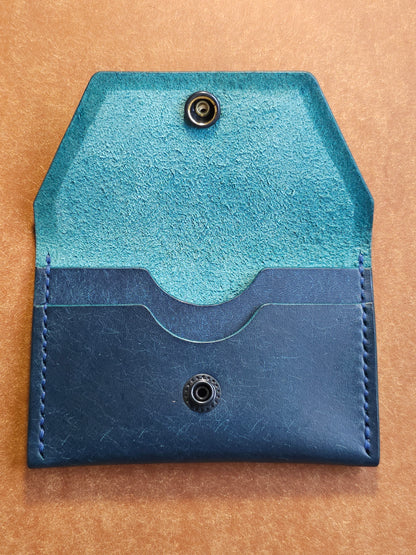 Inside of leather card holder with the snap unbuttoned. There are two interior pockets showing.