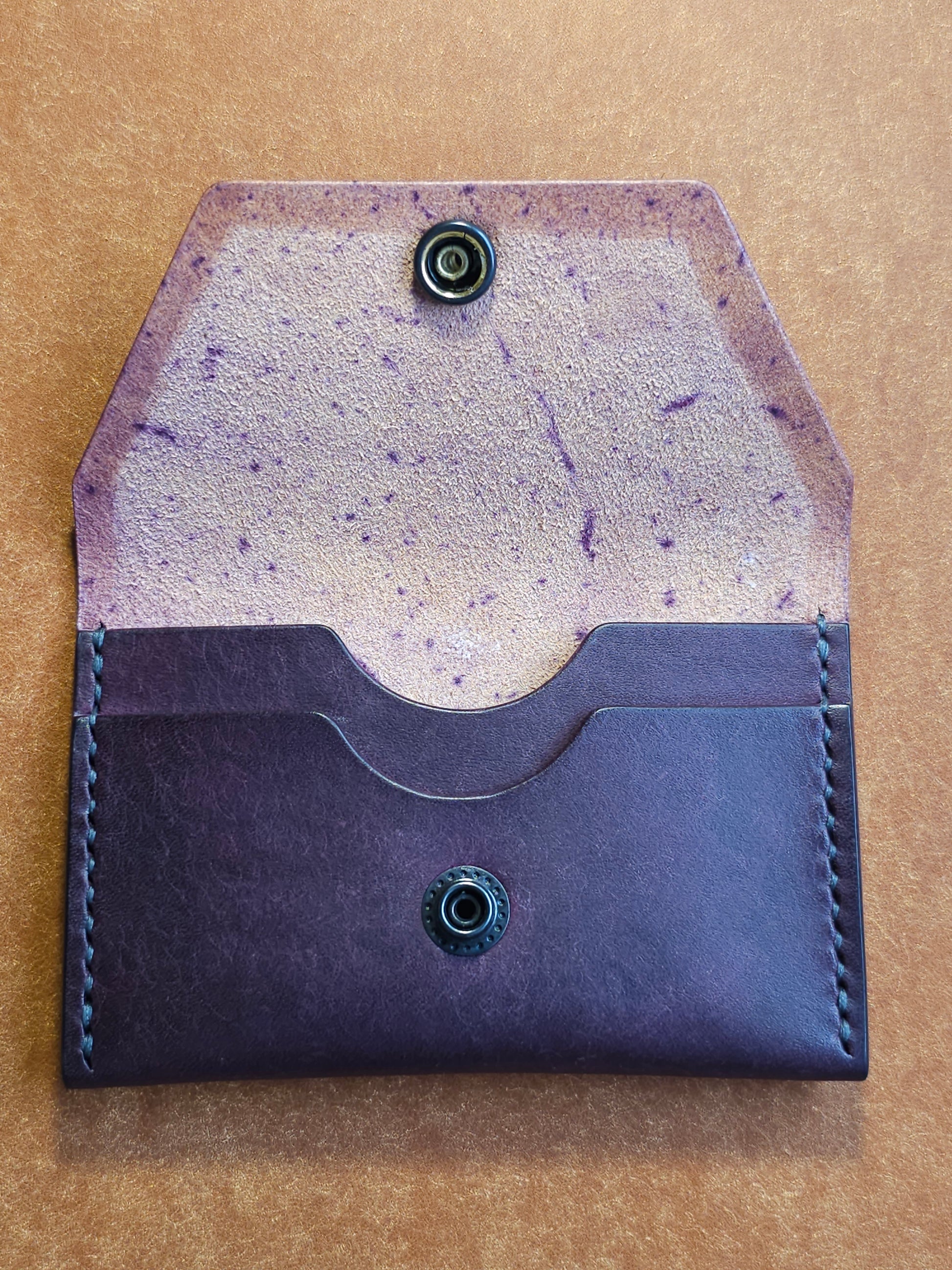 Inside of leather card holder with the snap is unbuttoned. There are two interior pockets showing.