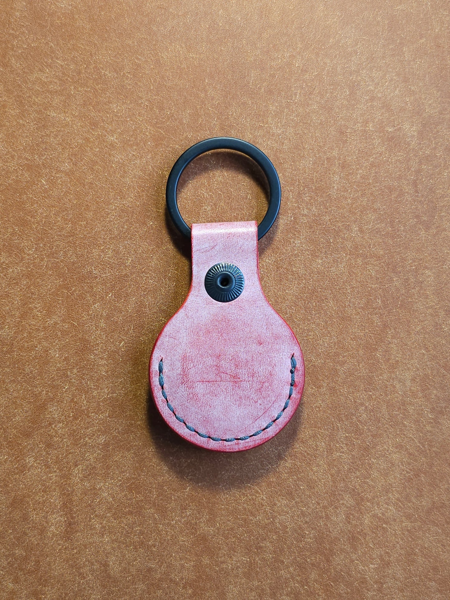 Back of circular leather air tag holder attached to black key ring.