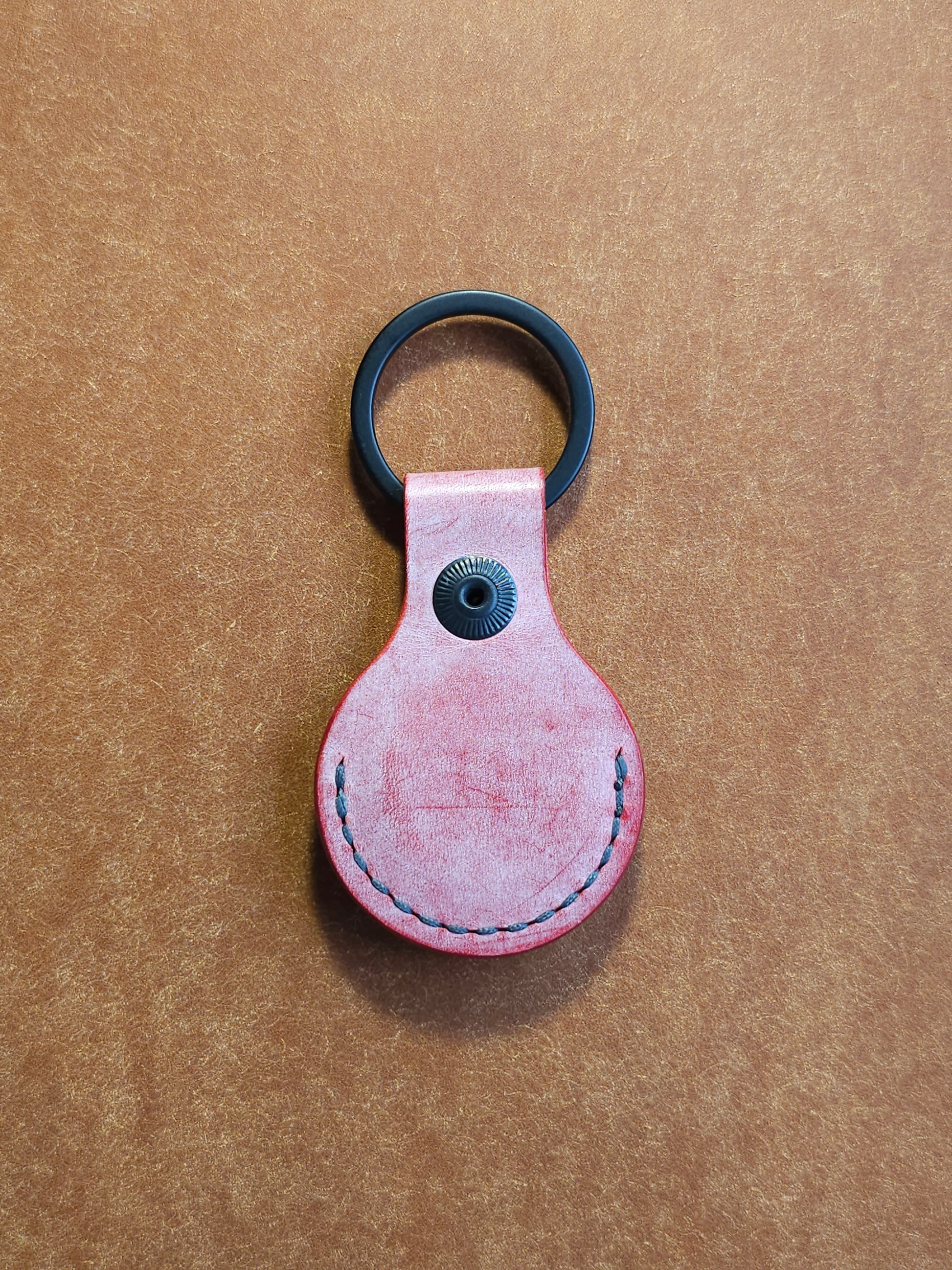 Back of circular leather air tag holder attached to black key ring.