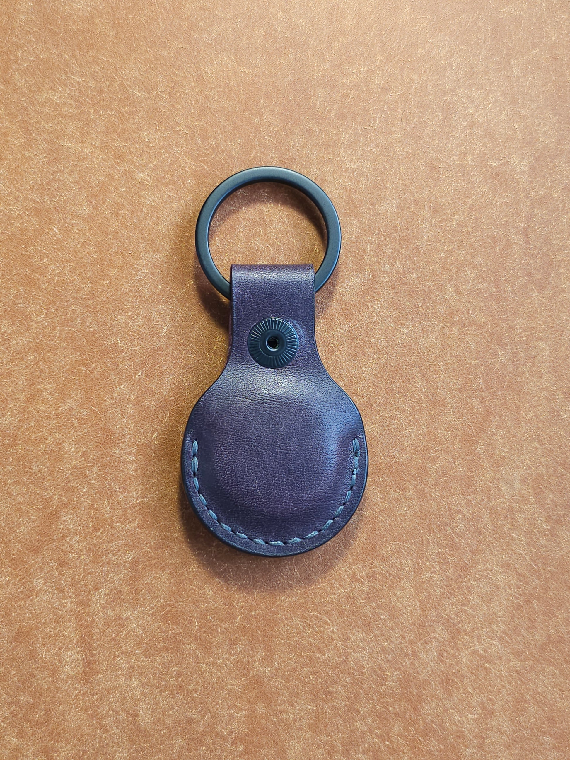 Back of circular leather air tag holder attached to black key ring.