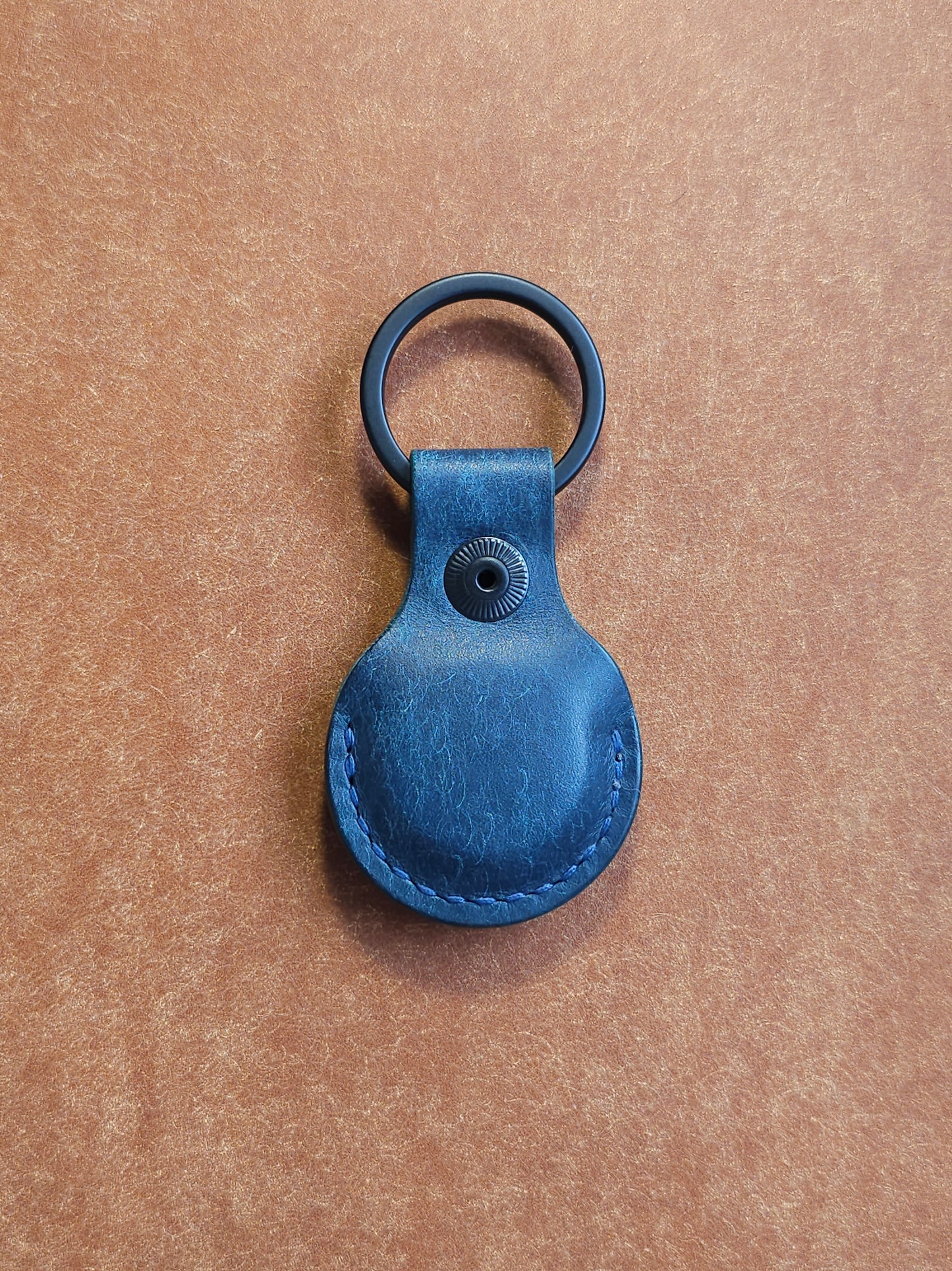 Back of circular leather air tag holder attached to black key ring.