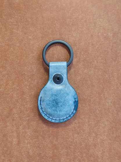 Back of circular leather air tag holder attached to black key ring.