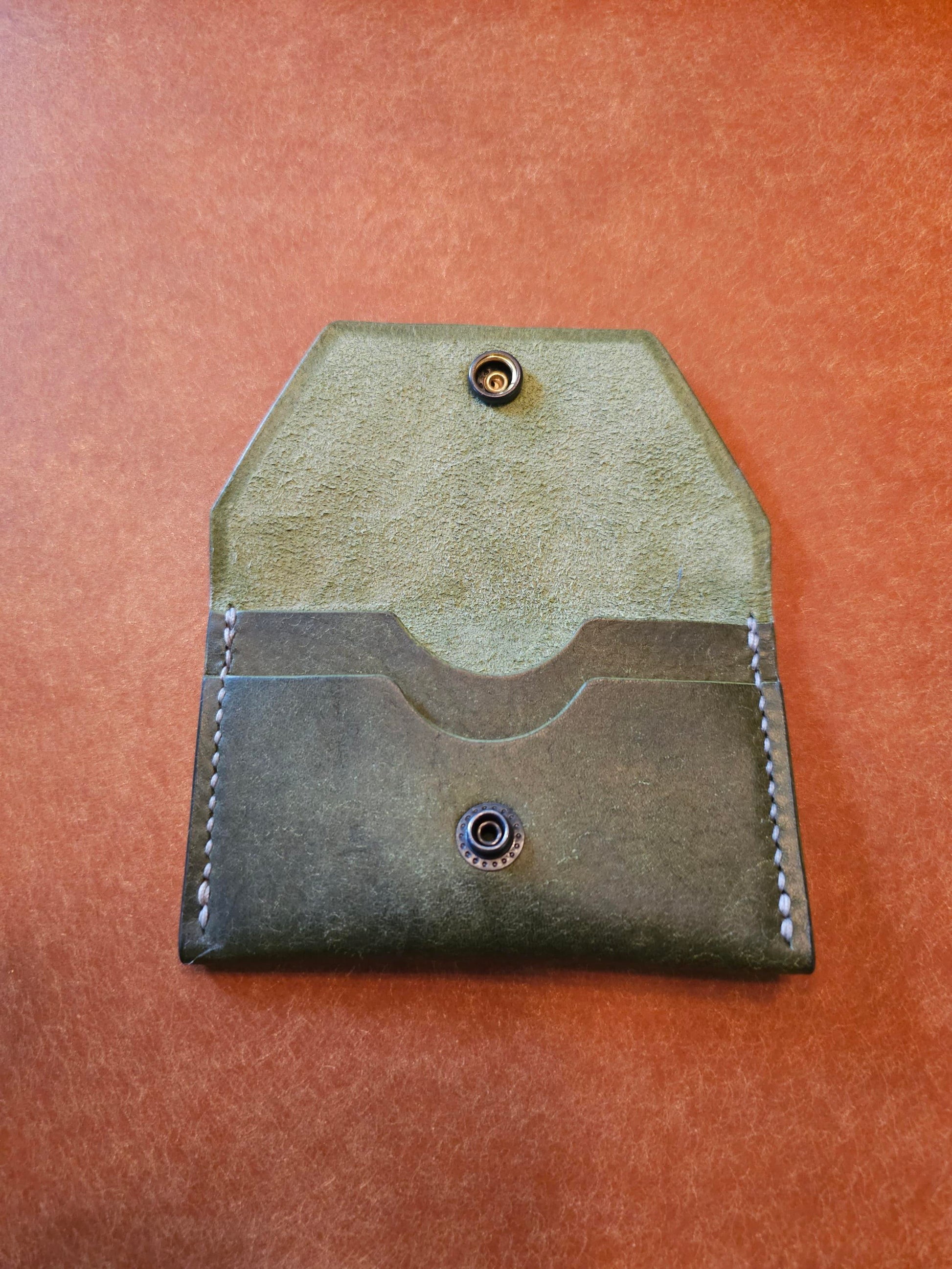 Inside of leather card holder with the snap is unbuttoned. There are two interior pockets showing.