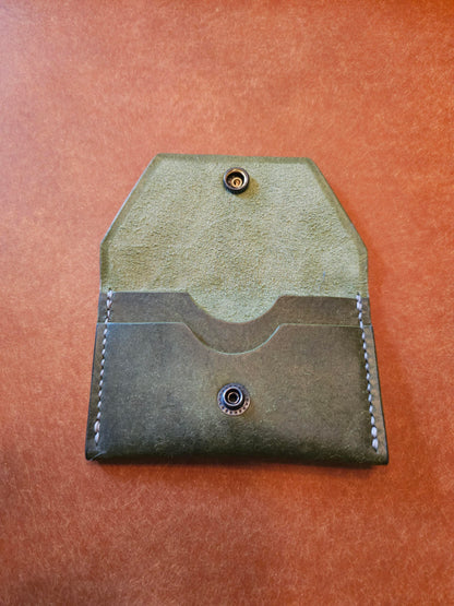 Inside of leather card holder with the snap is unbuttoned. There are two interior pockets showing.