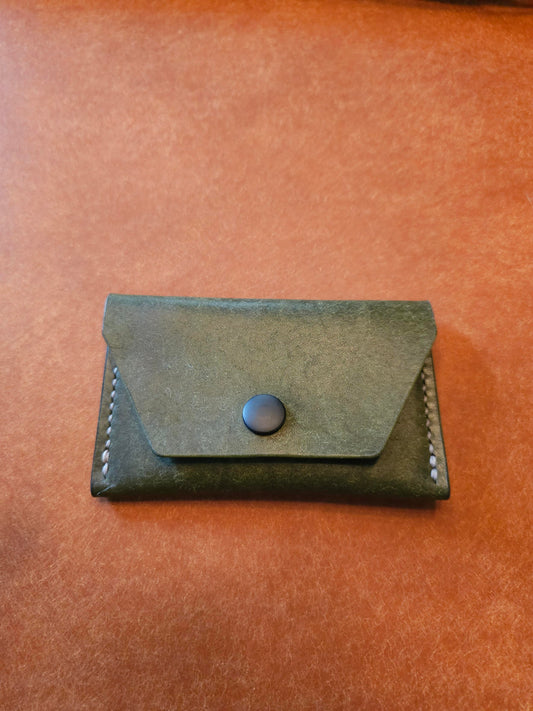 Front of leather card holder with angled pocket fastened with a snap.